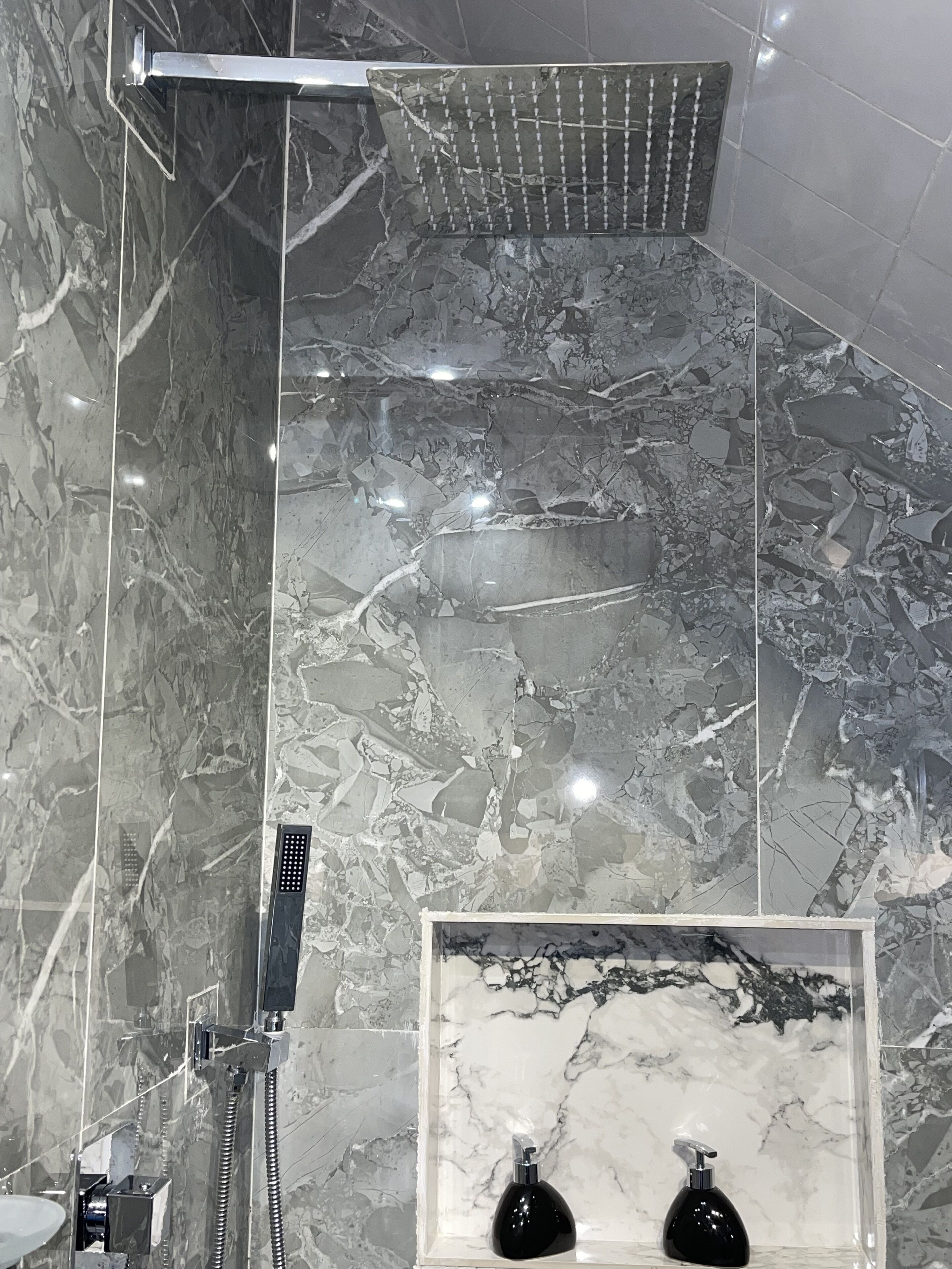 Un baño con ducha, espejo y lavamanos.