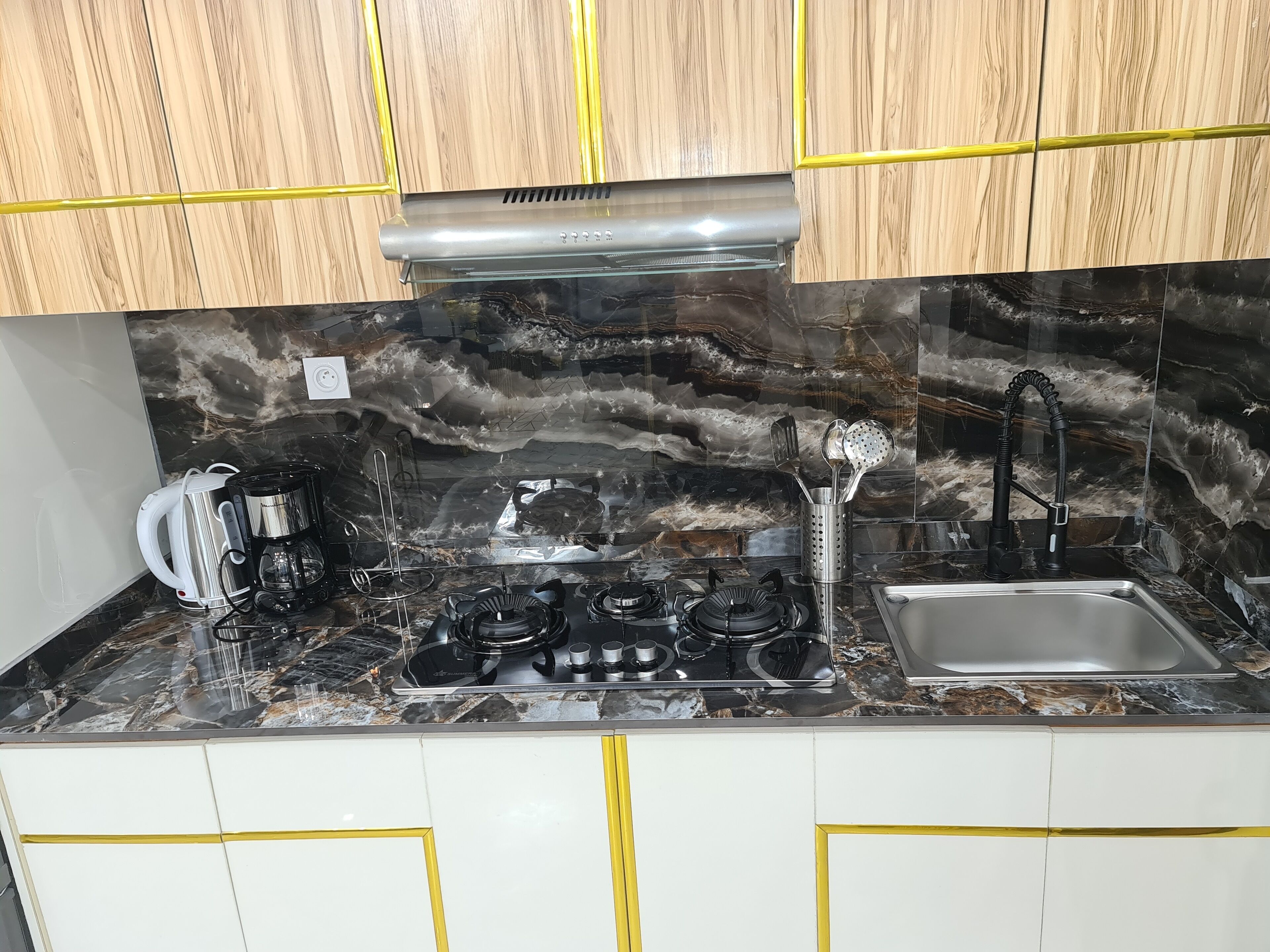 A kitchen with a gas stove, a coffee maker, and a sink.