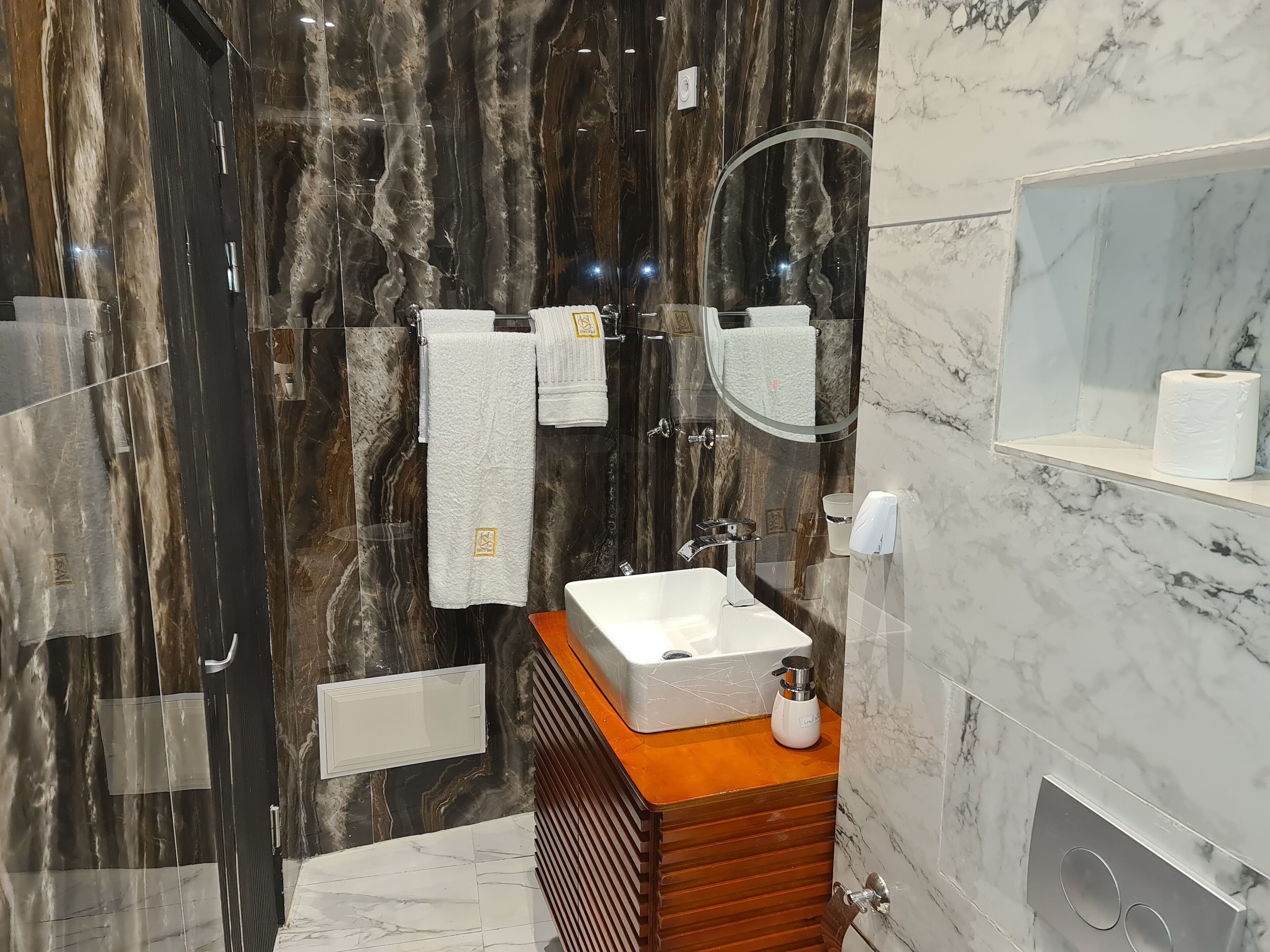 Un bagno moderno con un vanità in marmo, un lavandino e uno specchio.