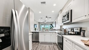 A modern kitchen with stainless steel appliances, white cabinetry, and a wooden floor. - GreenLinks at Lely Resort · King Bed · Lake View · Golf · Sleeps 6 (Naples)