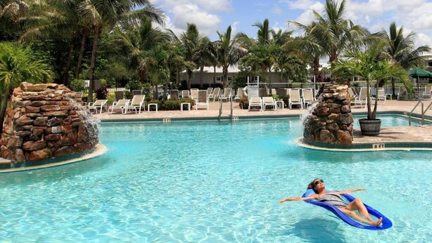 A swimming pool with lounge chairs and palm trees. - GreenLinks at Lely Resort · King Bed · Lake View · Golf · Sleeps 6 (Naples)