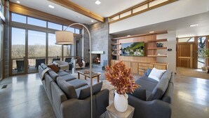 A spacious living area with a large sofa set, a fireplace, and a dining area with a view of the outdoors. - Corporate*Hot Tub•20 Acres•King Beds•Firepit•Views (Grove)