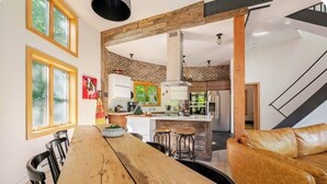 A modern kitchen with a central island, wooden beams, and a dining area with a large wooden table and chairs.