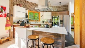 A modern kitchen with a central island, white cabinetry, and a brick accent wall.
