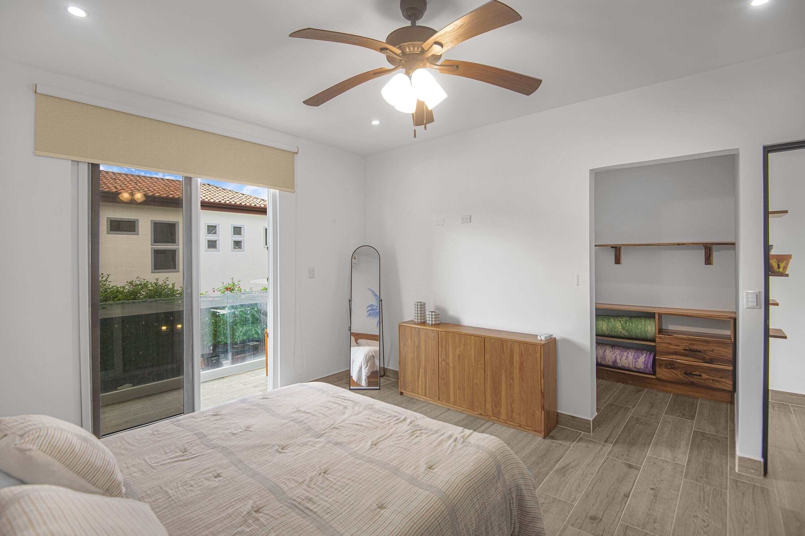 Ein Schlafzimmer mit einem Bett, einem Deckenventilator, einem Spiegel und einem Kleiderschrank.