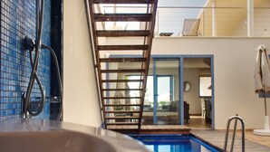 Une piscine avec un escalier en bois, un espace douche et une vue sur l’intérieur.