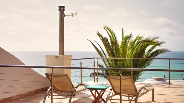 Un balcon avec deux chaises et une table, donnant sur la mer.