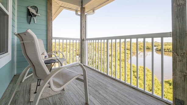 A balcony with a view of a water body and vegetation. - Nature's Landing C302 Pool and Amazing Water View! (Cedar Key)