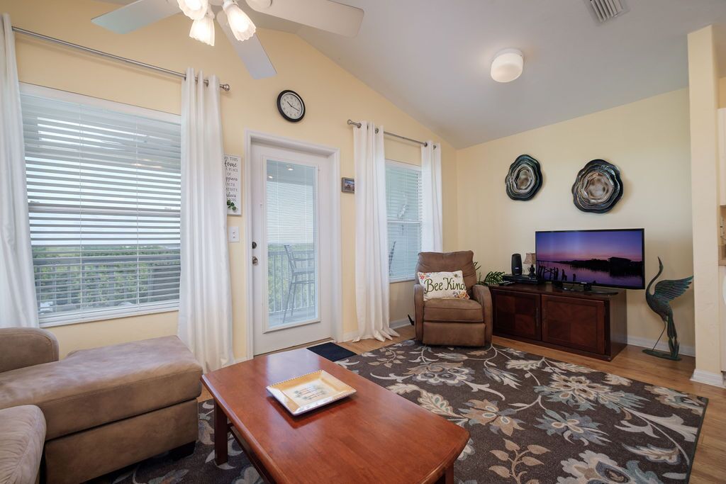 A living room with a sofa, a coffee table, a chair, a television, and decorative plates on the wall.