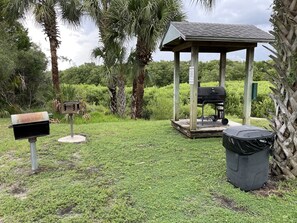 Relax under the gazebo, surrounded by lush greenery, with a barbecue grill and mailbox nearby.