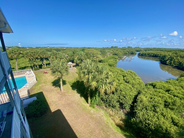 Relax by the serene pool surrounded by lush greenery and a tranquil river view.