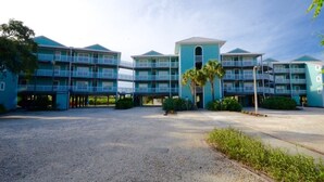 A multi-story hotel with a central atrium, balconies, and a gravel driveway. - Nature's Landing C302 Pool and Amazing Water View! (Cedar Key)