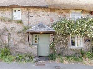 A stone building with a thatched roof, a green door, and a small porch area. - 1 bedroom accommodation in Poundsgate, near Newton Abbot (Poundsgate, near Newton Abbot)