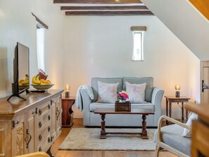 A cozy living room with a sofa, a wooden coffee table, a TV, and a fruit bowl.