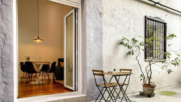 A dining area with a table and chairs, a potted plant, and a window with bars.