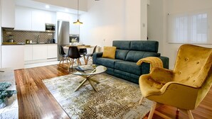 A modern living room with a sofa, a yellow armchair, a glass coffee table, and a patterned rug.
