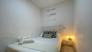 A neatly made bed with white linens and a geometric patterned pillow, a bedside table with a lamp, and a motivational quote on the wall. - Madrid Delicias II - One-bedroom apartment (Madrid)