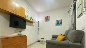 A small, modern living room with a grey sofa, a wooden cabinet, a flat-screen TV, and a small table. - Madrid Delicias II - One-bedroom apartment (Madrid)