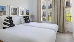 A hotel room with two beds, a window with curtains, a lamp, and framed pictures on the wall. - Madrid Pacífico - Nex to Retiro Park (Madrid)