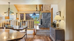 A spacious kitchen with a wooden ceiling, a stone fireplace, and a view of the outdoors. - Lone Peak Lookout l Big Sky Golf Course (Big Sky)
