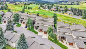 A residential area with modern houses, a golf course, and a mountain in the background. - Lone Peak Lookout l Big Sky Golf Course (Big Sky)