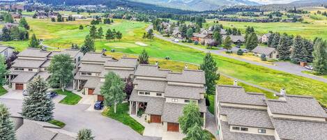 A residential area with modern houses, a golf course, and a mountain in the background.