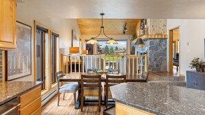 A spacious kitchen with a large island, wooden cabinetry, and a stone fireplace. - Lone Peak Lookout l Big Sky Golf Course (Big Sky)