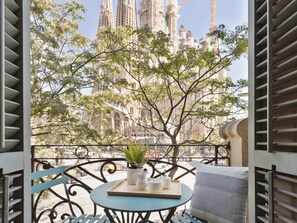 Un balcon offrant une vue sur la Sagrada Familia, avec une table agrémentée d’une plante, d’un plateau et d’un coussin.