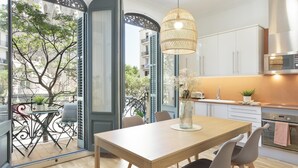 Une cuisine moderne avec des meubles blancs, une table à manger en bois et un luminaire suspendu.