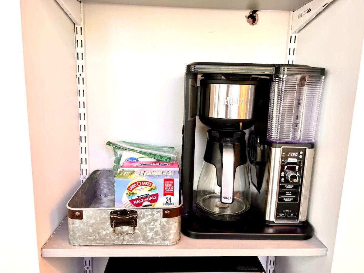 A coffee maker and a container of creamer on a shelf.
