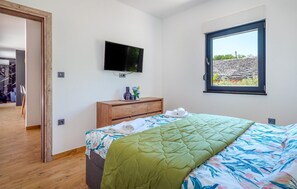 Relax in this serene bedroom with a large bed, flat-screen TV, and a beautiful view.