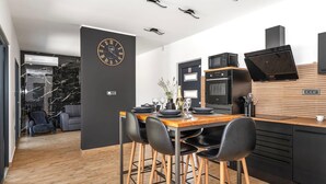 A modern kitchen with a wooden dining table, black chairs, and a black clock on the wall. - Nice home in Trbounje with WiFi (Trbounje)