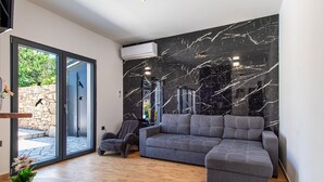 A modern living room with a grey sectional sofa, a stone wall, and a large window. - Nice home in Trbounje with WiFi (Trbounje)