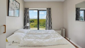 Une chambre à coucher avec un lit, une lampe de chevet, un radiateur et une fenêtre avec des rideaux.