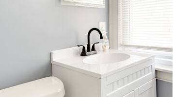 A bathroom with a white toilet, a white sink with a black faucet, and a mirror above the sink.