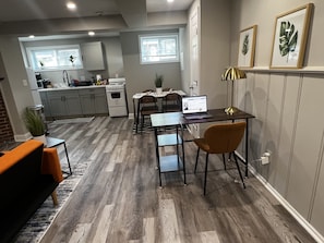 Una cucina moderna con mobili grigi, un piano cottura bianco e un'area pranzo con tavolo e sedie.