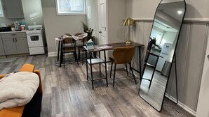 Un espace de vie compact comprenant un coin repas, un mur miroir et une petite cuisine.