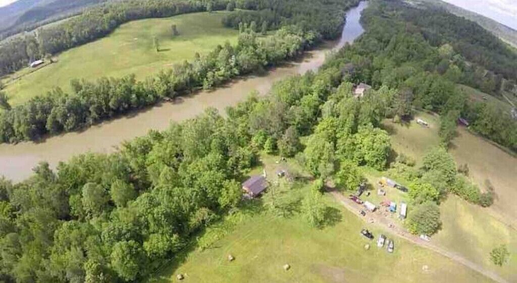 Luchtbeeld van een landgoed in een landelijke omgeving, met een rivier, dicht bos en verspreide gebouwen.