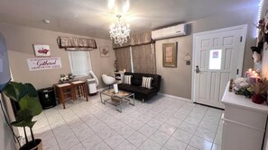 A living room with a sofa, a coffee table, a chandelier, and a door with a sign.