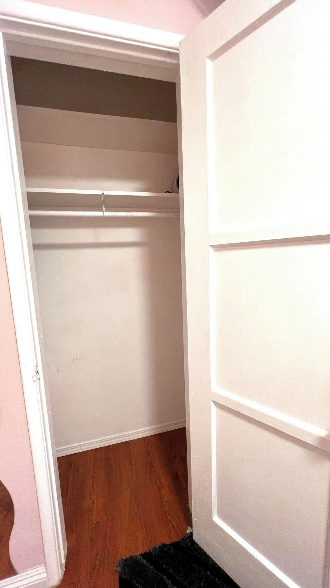Ein Schrank mit Holzboden und weißen Türen.