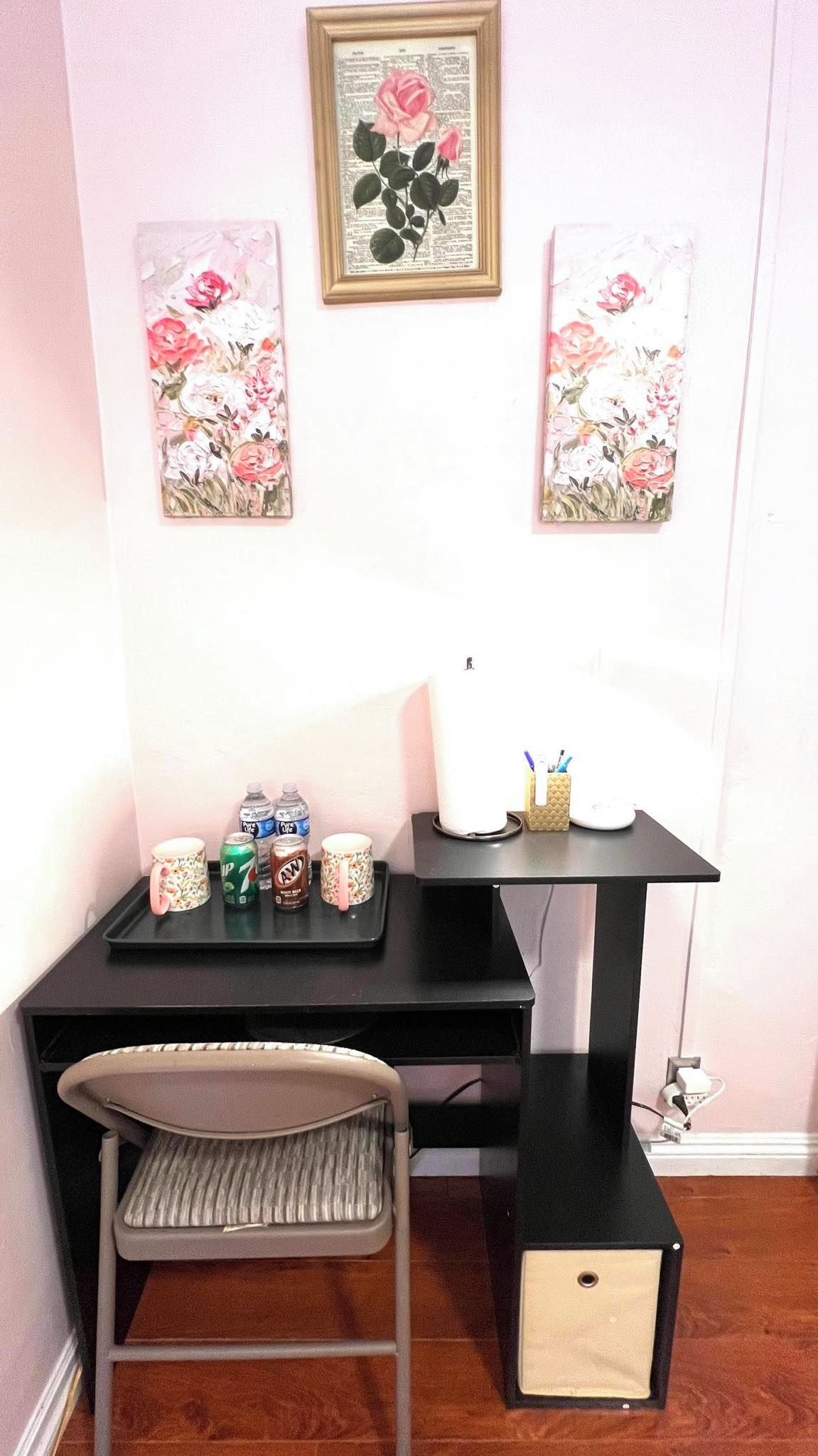 A desk with a chair, a framed botanical illustration, and a tray with various items.