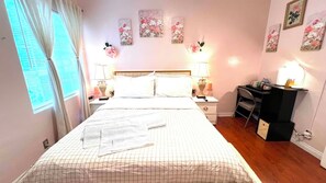 Un dormitorio con una cama, dos mesitas de noche, un escritorio y una silla.