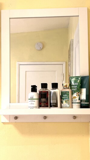 A mirror with a shelf below it displaying various personal care products.