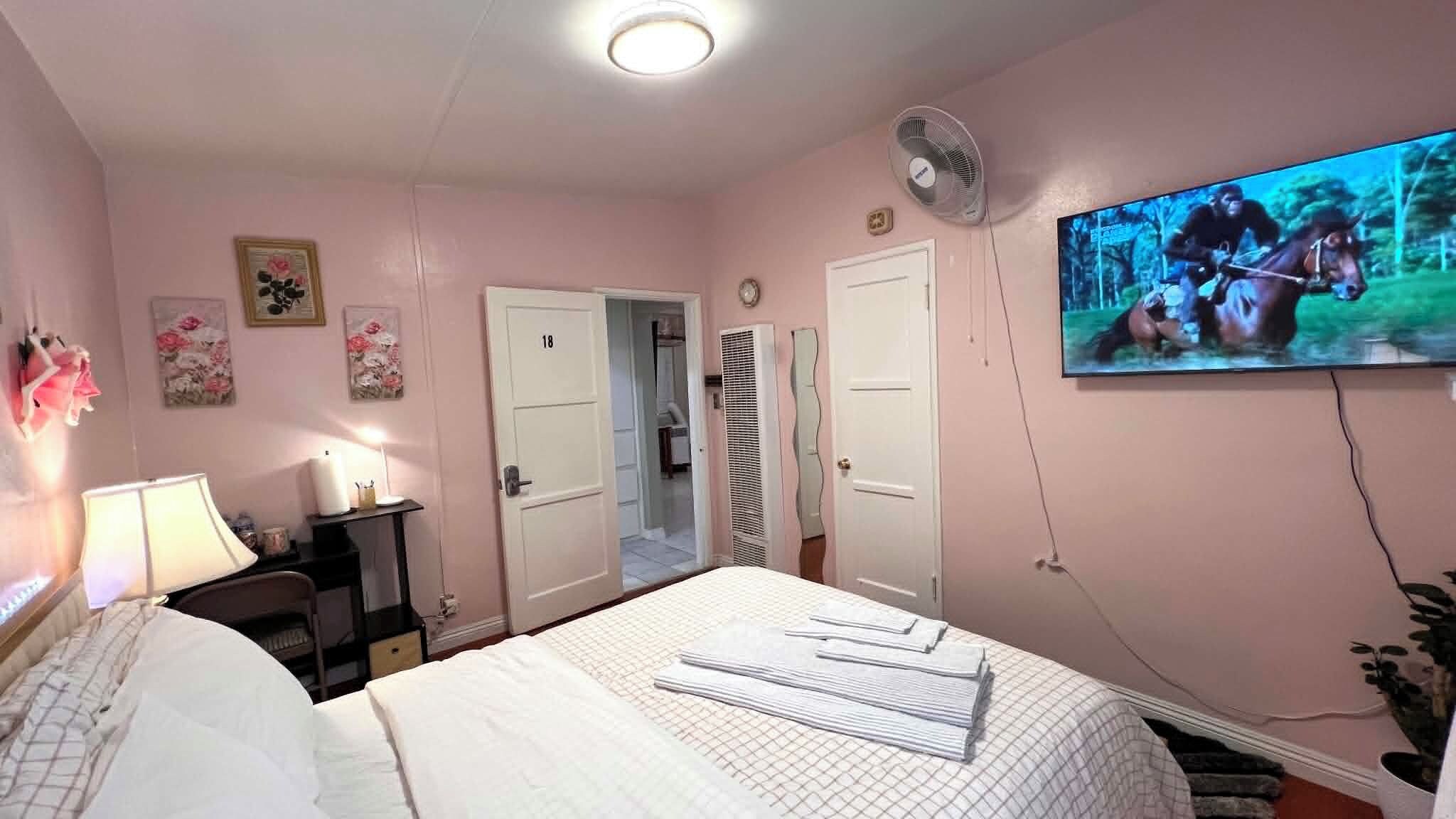 Ein Hotelzimmer mit einem Bett, einem Fernseher, einem Schreibtisch und einer Tür zum Badezimmer.