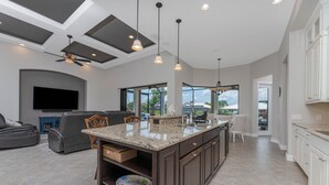 Una cocina moderna con una isla central, muebles oscuros e iluminación colgante.