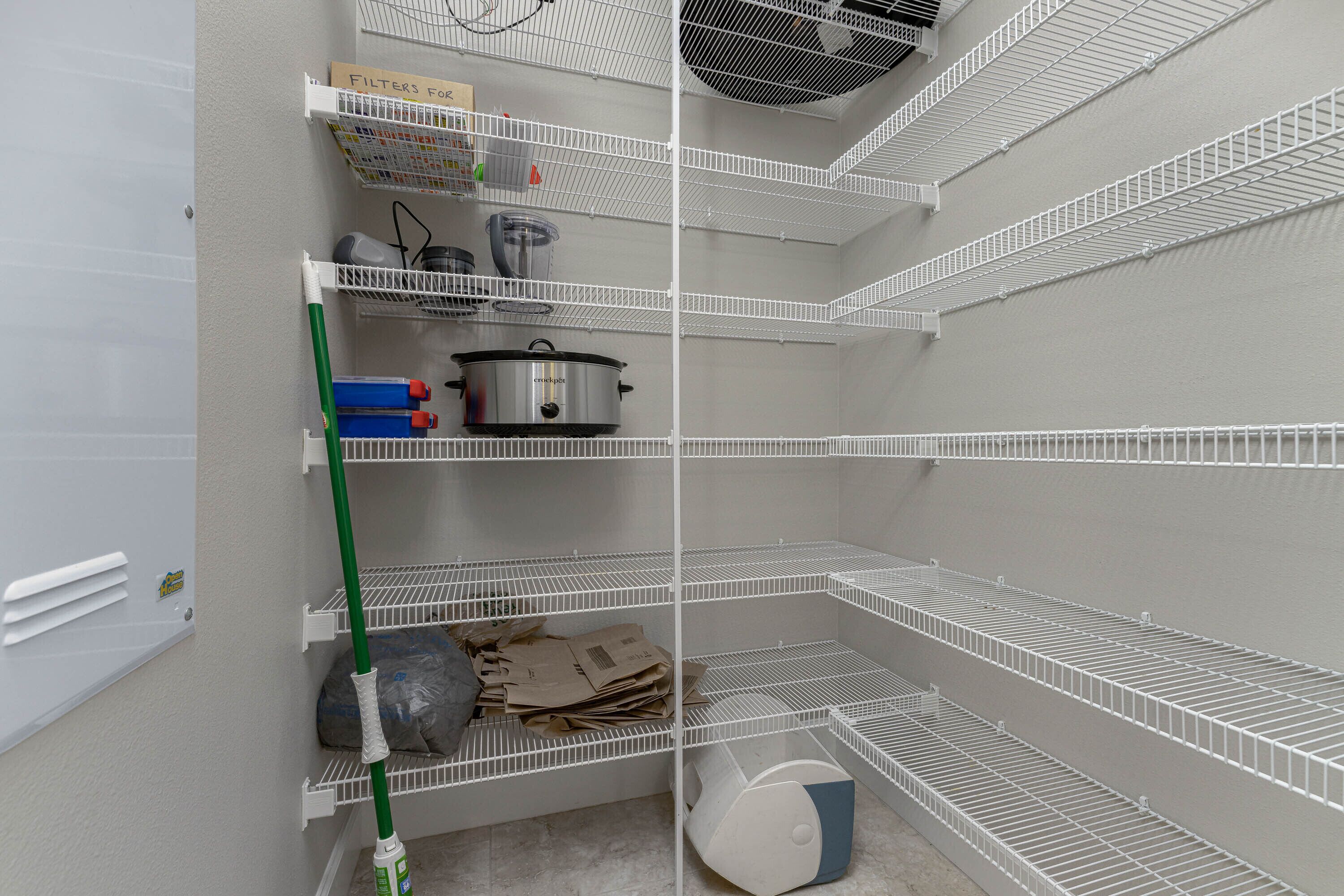 A storage closet with metal shelves, a mop, a pot, and some boxes.
