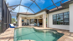 Una piscina con techo de cristal, un patio con sillas y vistas al jardín trasero.