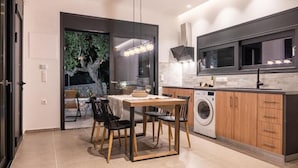 A modern kitchen with a dining area, a washing machine, and a large window. - Casatino Villas #1 (kalianeika)