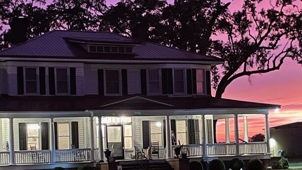 A large, two-story house with a porch and a covered front porch area.