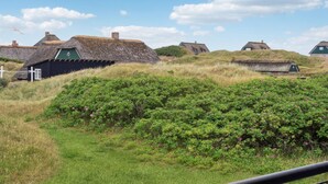 A rural landscape with traditional thatched-roof houses, surrounded by lush greenery and flowering bushes. - Amazing apartment in Fanø with WiFi (Fanø)